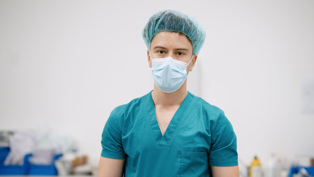 Doctor standing in a hospital or clinic, wearing scrubs, a medical mask, and a surgical cap, ready for healthcare work