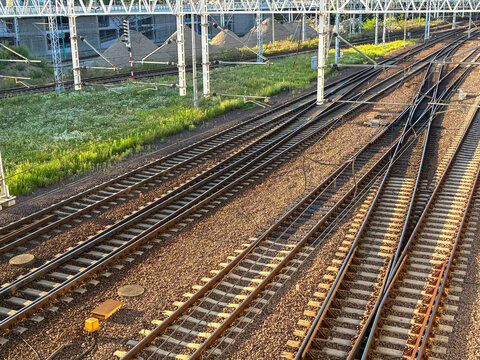 Parallel railway tracks intersecting in an industrial landscape, representing logistics, transportation infrastructure, travel connectivity, and long distance modern journey concepts