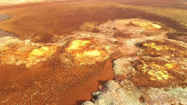 Aerial view of vibrant yellow and orange mineral deposits and salt crusts in the volcanic landscape of the Dalol geothermal area in Dalol, Afar, Ethiopia.