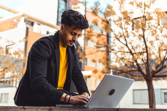 Young Moroccan man focusing on his laptop, embracing remote work and digital entrepreneurship in an urban setting