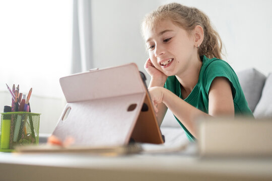 Happy schoolgirl learning with tablet at home