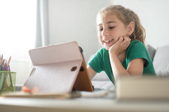 Happy schoolgirl learning with tablet at home