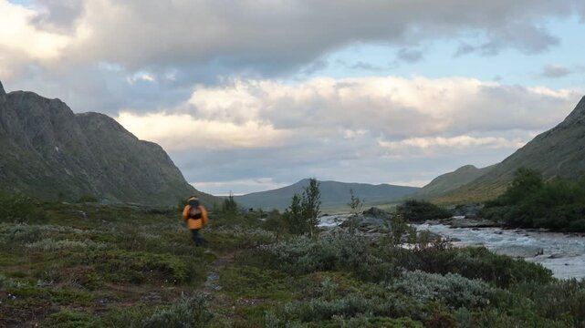 Beautiful european family with children and pet dog hiking Knutshoe summit with blue lake in mountain landscape in Jotunheimen National Park in Norway, mountains of Besseggen in background, cloudy sky