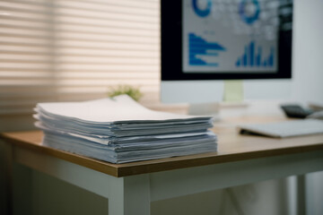 Fototapeta premium Stack of business documents on office desk with computer