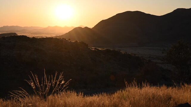 Sunset in the Namibian desert, the sun sets behind the mountain.