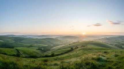 Fototapeta premium Sunrise over green rolling hills and misty valley landscape at dawn