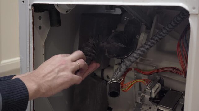 man finding coins inside a clogged washing machine drain pipe, Foreign objects in washing machine, technician removing money from broken appliance