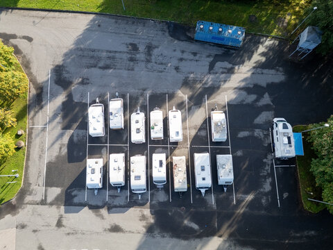 Aerial view of several caravans and trailers parked in orderly rows within a paved parking lot surrounded by trees in Kempele, North Ostrobothnia, Finland.
