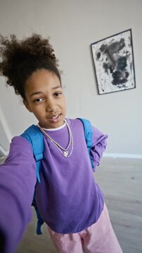 Portrait of African American teenager with backpack recording selfie video blog inside art gallery. Clip is ideal for museum marketing, youth education campaigns, or social media content, vertical