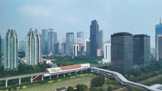 Jakarta, Indonesia - 17 July 2026: Aerial view of the modern skyline featuring glass skyscrapers, a monorail line, and lush greenery in the city center.
