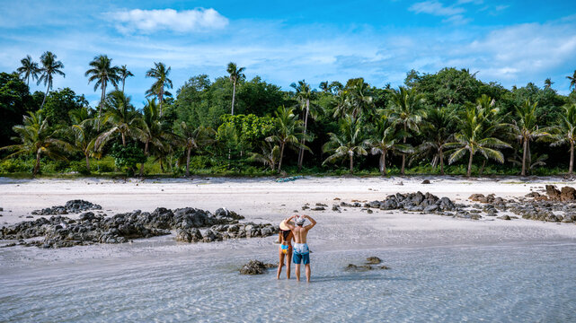 Couple tourist stay happy moment at the edge of the sea beach under shallow of the crystal clear water in summer trip on tropical island island