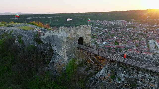 Tourist walking wooden bridge medieval Ovech fortress gate Provadia city view cliff top aerial drone perspective summer travel vacation landmark Bulgaria