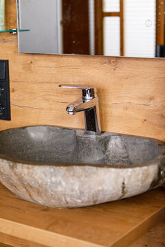 Close-up of a stylish bathroom sink made from natural stone with a contemporary chrome faucet.