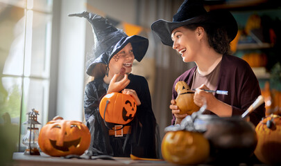 Naklejka premium Mother and Daughter Carving Pumpkins Together in Witch Costumes