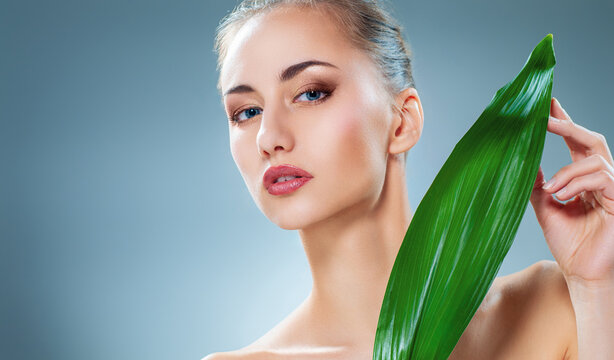 Beautiful Woman with Fresh Green Leaf Promoting Natural Skincare