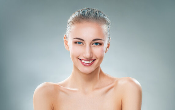 Beautiful Smiling Woman with Perfect Skin on Gray Studio Background