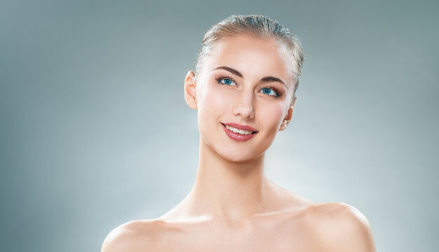 Beautiful Young Woman with Perfect Skin Smiling on Grey Background
