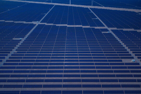 Solar photovoltaic panels at sunrise/sunset; wind turbine power plant; new energy