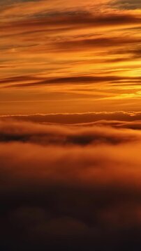 Stunning golden sunset view above thick rolling clouds captured in vertical cinematic motion.