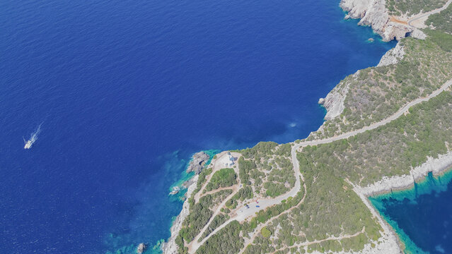 Aerial view of Cape Lefkatas lighthouse on steep rocky cliffs at southern tip of Lefkada island surrounded by deep blue Ionian sea Greece horizontal stock photo