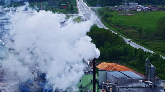 Industrial paper mill factory emission plume from high smokestack in aerial view.