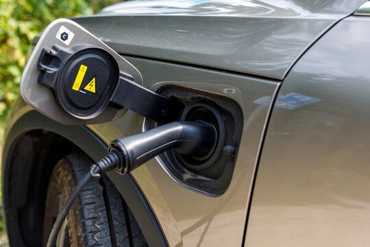 Close-up of an electric vehicle (EV) charging with a plug connected to the car's port.