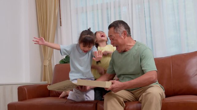 Grandfather sharing a family meal with two young granddaughters at home. The warm scene conveys family bonding, caregiving, childhood, and quality time across generations.