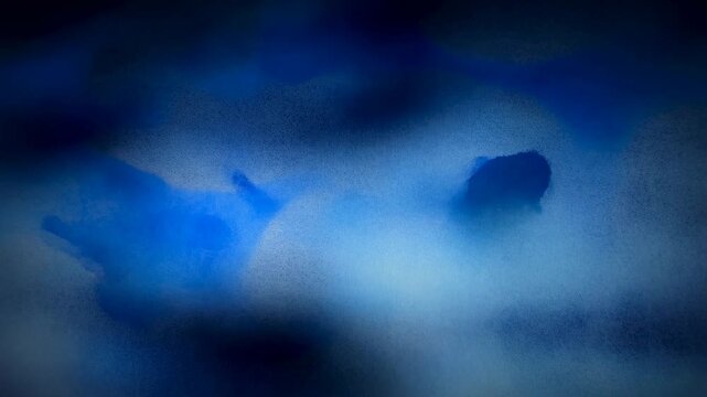 Blue ink blobs spread and diffuse smoothly in a dark liquid environment with soft blurred edges. Smooth wave movement creates soft blur and visible depth.