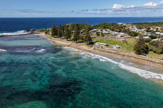 Aerial view of Brooms Head Beach and rocky headland, showing the sandy shoreline, Pacific Ocean, surrounding coastal landscape and township of Brooms Head along the Clarence Valley coast