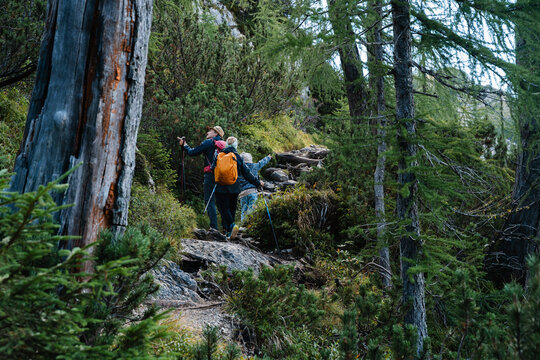 Family with kids walking on wild mountain trail. Happy active parenting and healthy outdoor family lifestyle.