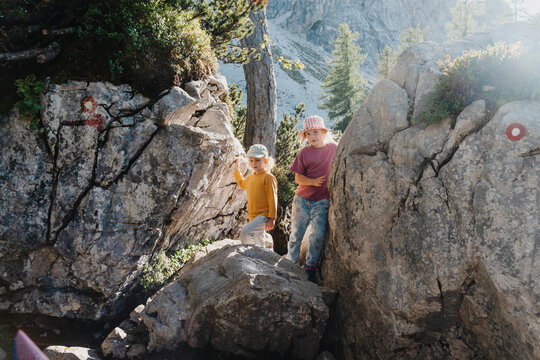 Cute smiling child hiding inside natural rock cave. Happy family vacation with children and fun outdoor summer camp.