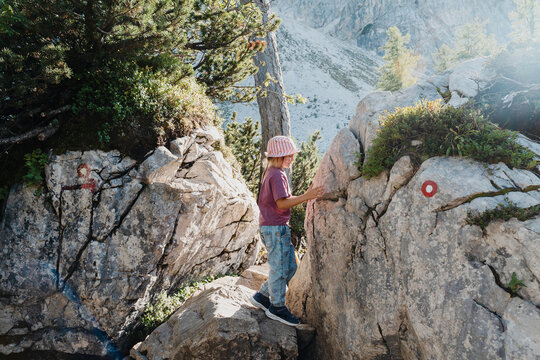 Cute smiling child hiding inside natural rock cave. Happy family vacation with children and fun outdoor summer camp.