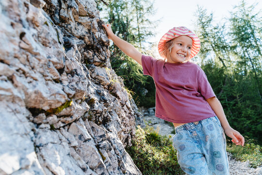 Beautiful smiling girl in striped hat in sunny bright nature. Happy healthy childhood and wonderful family summer vacation.