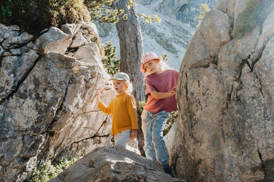 Cute smiling child hiding inside natural rock cave. Happy family vacation with children and fun outdoor summer camp.