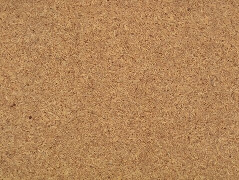 Full frame background texture of compressed particle board surface, showing rough wooden fibers, natural beige brown color, and detailed industrial material composition for design overlay