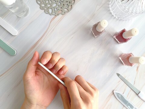 ネイルファイルで爪を整える女性の手/ネイルケアイメージ