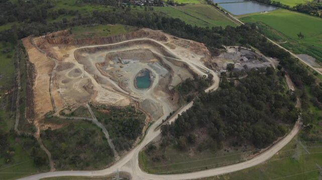 Melbourne, VIC, Australia - 20 August 2026: Aerial view of a quarry with a central pond, surrounding rocky terrain, and dense vegetation.