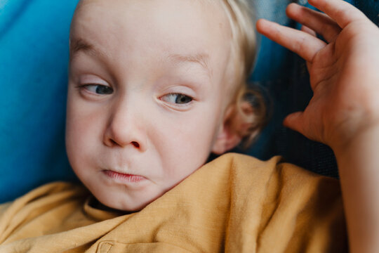 Funny little boy making a silly face while relaxing in a blue hammock outdoors