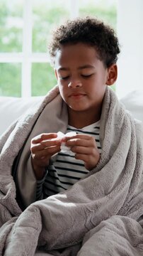 Tissue, fever and child blowing nose on sofa for recovery of allergy infection, flu or cold. Sneeze, sick and boy with symptoms in living room for healing with illness, sinus or congestion in home
