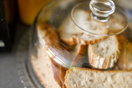 Close-up of freshly baked artisan bread slices stored under a clear glass cloche.