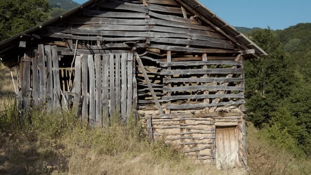 Close view of an ancient traditional wooden barn built with wattle and mud walls in a rural mountain setting on Stara Planina, Serbia. Authentic historic architecture footage.