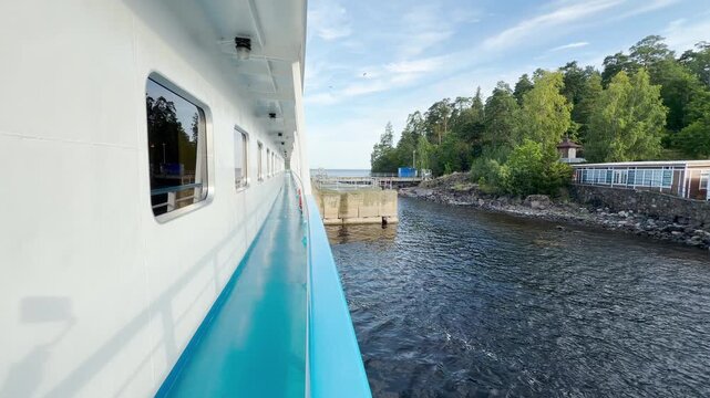 A cruise ship deck navigates along a scenic pier at Valaam, Lake Ladoga. This peaceful journey brings calm and happy feelings during a wonderful vacation.