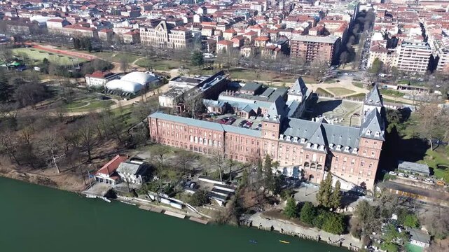 Aerial drone view of Castello del Valentino palace in Valentino Park with Turin city skyline and snowy Alps in background, Turin, Italy