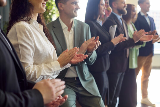 Audience businesspeople colleagues give applause at seminar training. Side view of managers and team clapping during a corporate workshop indoors. Essential concept of applause motivation.