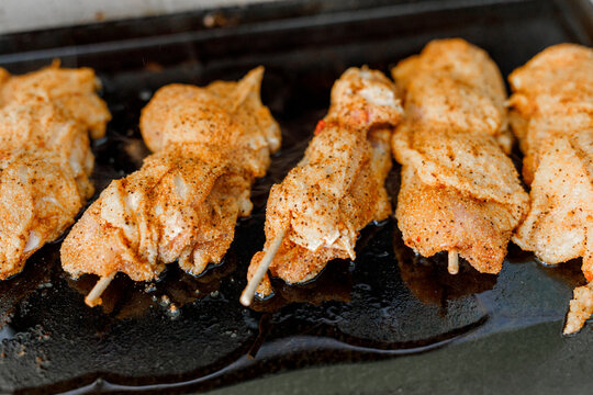 Close-up of delicious spiced meat skewers sizzling on a hot griddle, ready to eat.