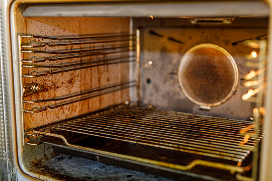 Close-up of a very dirty oven interior with grease, grime, and burnt food residue on walls and racks