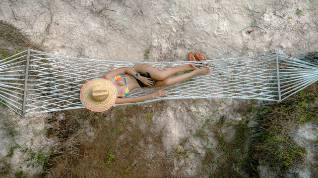 Woman tourist stay under shadow of the coconut trees at the edge of the sea beach, cheerfully traveling life in summer of the island