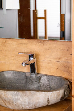 Stylish natural stone basin with modern chrome faucet and wooden details in a contemporary bathroom.