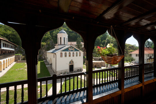 Pljevlja, Montenegro - 30 July 2005: View of Holy Trinity Monastery with its white walls and domed roof, seen from a wooden balcony with a hanging flower basket in the foreground.