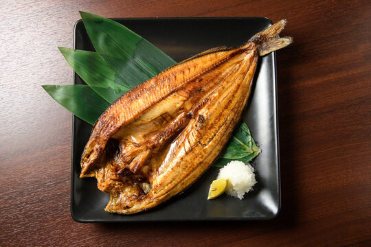 Charcoal-grilled Hokkaido hokke fish beautifully plated with ginger and white rice, showcasing Japanese culinary elegance and authentic seafood preparation